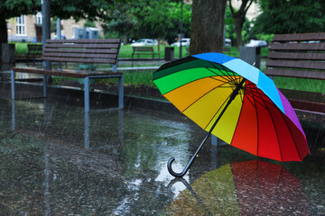 Colorful umbrella on wet asphalt outdoors, space for text