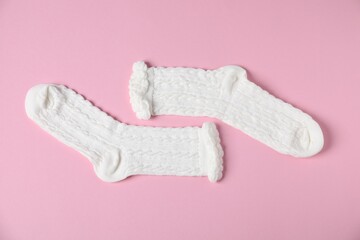 Pair of comfortable white socks on pink background, top view