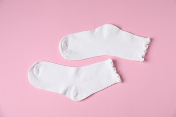 Pair of comfortable white socks on pink background, top view