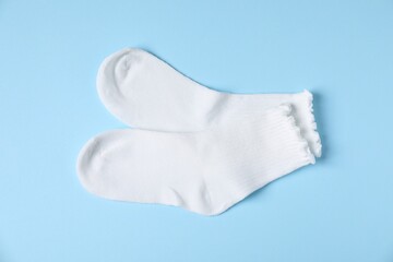 Pair of comfortable white socks on light blue background, top view