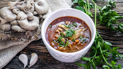 Savory blue oyster mushroom soup garnished with fresh parsley and garlic on rustic wooden table