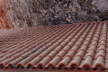 A beautiful, even roof covered with tiles from a building hidden under a rock