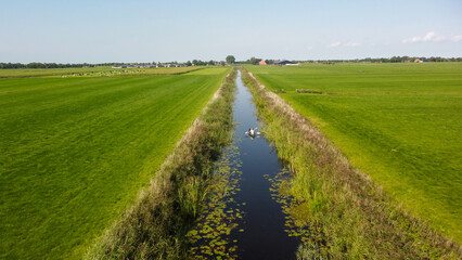 rural canal in a field in the typical dutch countryside with a couple on a kanoe