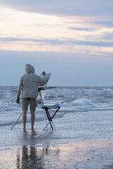 A painter painting the waves on a windy day