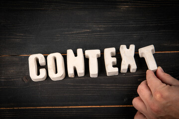 Word Context Formed by Concrete Letters with Hand on Dark Wooden Background