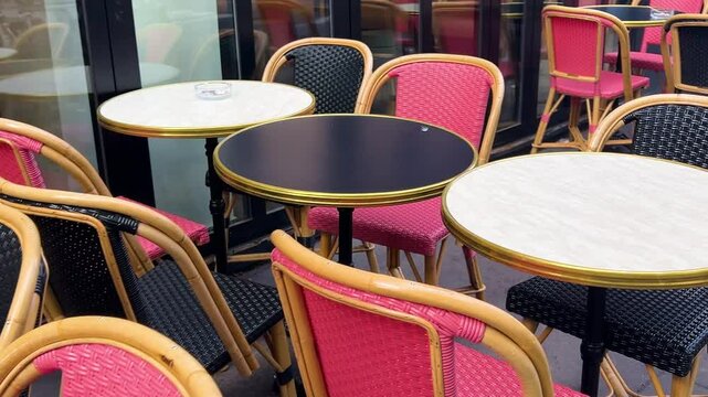 Bright pink and black wicker chairs with black and white round tables on an outdoor terrasse or summer veranda in the trendy Marais district of Paris, France.
