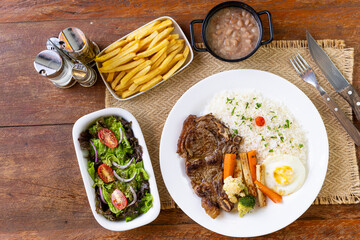 Prato Executivo Brasileiro de bisteca de boi com Arroz, Batata Palha, feijão, farofa e Salada em...