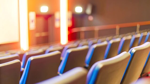 Rows of empty seats in a theater with bright lights illuminating the screen area