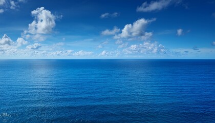 Obraz premium vast blue ocean under a sunny sky with fluffy white clouds and calm water stretches to the horizon creates tranquil scene