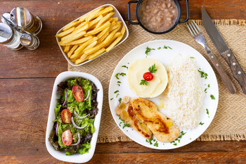 Prato Executivo Brasileiro filé de frango com Arroz, Batata Palha, feijão e Salada em Mesa de Madeira