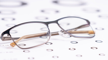 Eyeglasses On White Table Symbols For Close-Up Visual Acuity Test. Concept of wearing optical glasses for human vision correction. Deterioration of vision with age. Vision test method