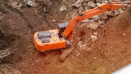 Orange excavator close-up working at construction site excavation pit dismantling old pavements...