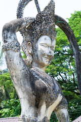 Ancient stone statue touching its ornate headdress in buddha park, vientiane, laos