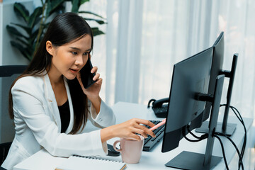 Working young Asian businesswoman calling to customer to present marketing online strategy...