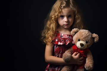 Sad little girl with a teddy bear on a black background. Halloween theme. Evil Clown. Horror movie Concept. Halloween Concept with Copy Space.