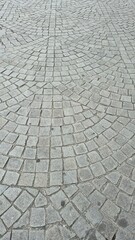Close-up of a cobblestone pavement with a fan-like pattern, taken outdoors during daylight in Porto, Portugal, showcasing historical urban design and traditional stone craftsmanship.