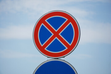 A round sign with a red circle and a blue background indicates no parking regulations. The bright...