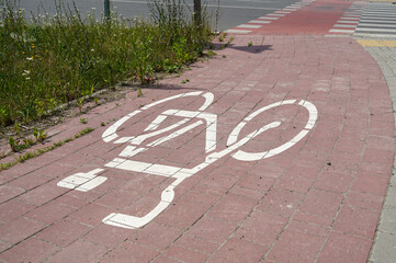 A bicycle lane symbol is prominently displayed on a brick sidewalk in an urban environment,...