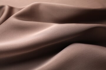 Crumpled light brown silk fabric as background, closeup