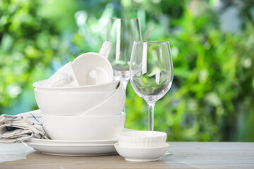 Different clean dishes on wooden table against blurred green background