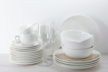 Different clean dishware on light wooden table near white wall
