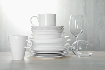 Different clean dishware on light wooden table indoors
