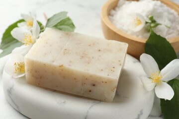 Soap bar, sea salt and jasmine flowers on table, closeup