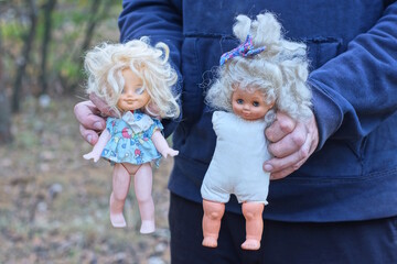 the hands of a man in blue clothes are holding two heads of a brown plastic dolls toys with blue...