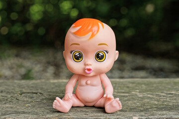 one small brown plastic toy doll sits on a gray table on a summer street