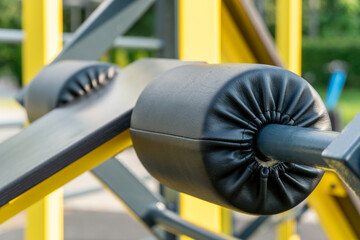 Padded weightlifting bars rest in a vibrant outdoor fitness area. Bright colors stand out against...