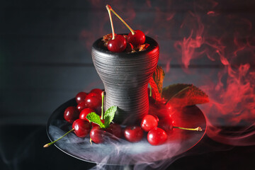Hookah with cherries and smoke on black background, closeup