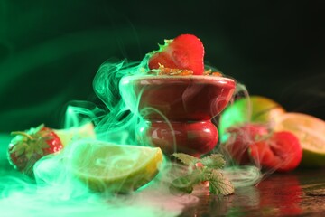 Hookah bowl with limes, strawberries, mint and smoke on black table, closeup