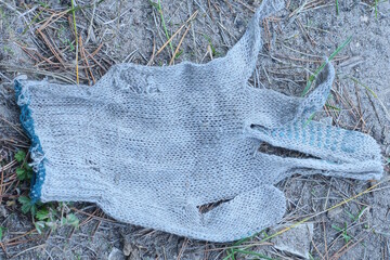 one old torn white work glove lies on the gray ground in the street