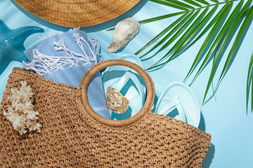 Flat lay composition with different beach accessories and palm leaf on light blue background