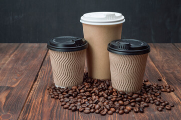 Mockup coffee in a disposable cup on a wooden table and coffee grains, dark background. Coffee background.