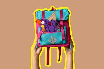 Hands holding schoolbag with different supplies on beige background