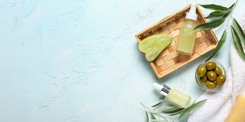 Natural cosmetic products with olive extract and guasha on light blue background with space for text