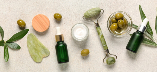 Natural cosmetic products with olive extract and massage tools on light background