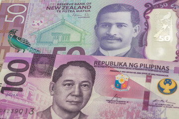50 New Zealand dollar and 100 Philippine peso banknotes. International trade concept