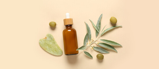 Bottle of natural essential oil, guasha and green olives on beige background
