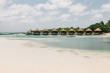 Luxury beachside bungalows surrounded by tranquil waters and lush greenery in a tropical paradise