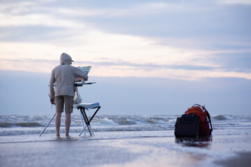 A man on the beach painting the sea 