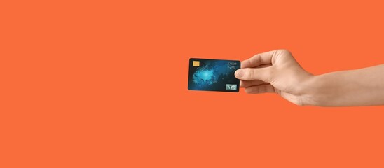 Hand with credit card on orange background
