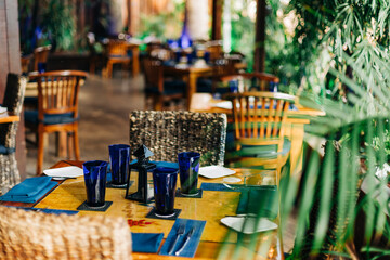 Dining area in a tropical restaurant surrounded by lush greenery during a sunny day
