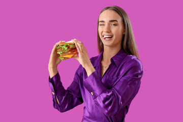 Beautiful young woman with tasty sandwich on purple background