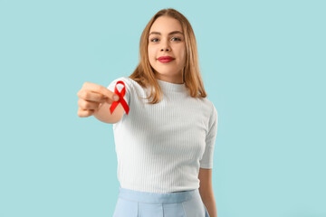 Young woman with red ribbon on blue background. AIDS concept
