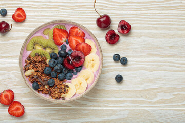 Vibrant acai bowl topped with fresh fruits like bananas, strawberries, kiwi, blueberries, cherries, crunchy granola for a healthy meal, breakfast or snack