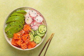Poke bowl, a traditional hawaiian dish with diced raw salmon, avocado, vegetables served with rice and vegetables, a healthy meal on green background, copy space