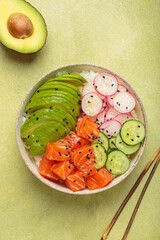 Poke bowl, a traditional hawaiian dish with diced raw salmon, avocado, vegetables served with rice and vegetables, a healthy meal on green background