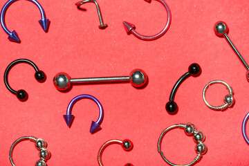 Composition with stylish jewelry for piercing on red background